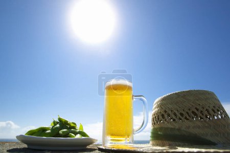 Téléchargez les photos : Bière avec pois verts et chapeau de paille sur fond de bord de mer - en image libre de droit
