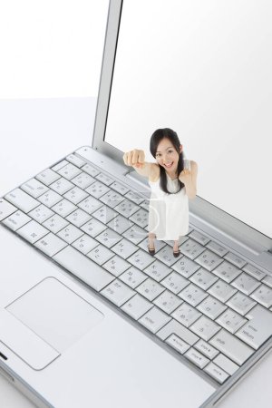 Foto de Diminuto asiático mujer de pie portátil teclado y mostrando puños - Imagen libre de derechos