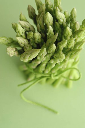 Téléchargez les photos : Un bouquet d'asperges vertes sur une surface verte - en image libre de droit