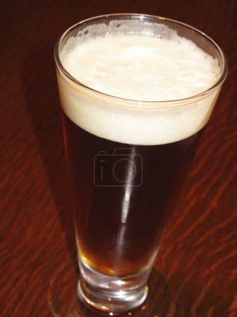 Photo for Beer glass with white foam on wooden table - Royalty Free Image