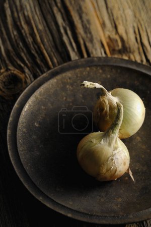 Téléchargez les photos : Deux oignons sur une assiette sur une table en bois - en image libre de droit
