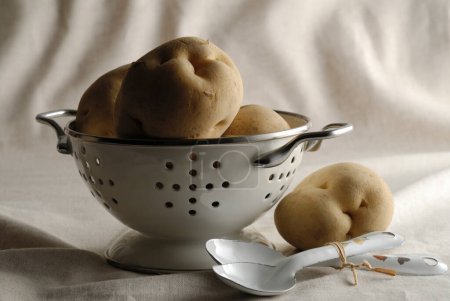 Téléchargez les photos : Une passoire avec des pommes de terre dedans et des cuillères - en image libre de droit