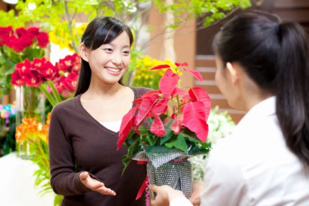 Téléchargez les photos : Portrait de jeune fleuriste japonaise avec cliente en boutique florale - en image libre de droit
