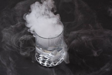 Weißer Rauch im Glas mit der Wirkung von Trockeneis auf dunklem Hintergrund