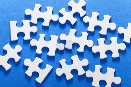Photo for A group of white puzzle pieces on a blue surface - Royalty Free Image