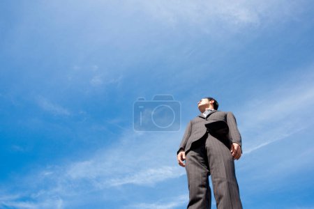 Téléchargez les photos : Portrait de beau adulte asiatique homme d'affaires sur fond bleu ciel - en image libre de droit