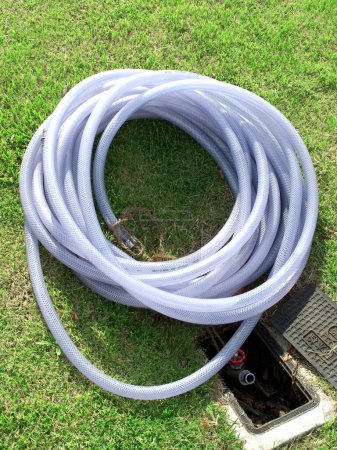 water supply hose in the garden on background, close up