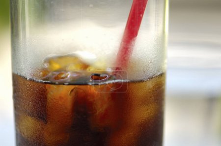 Foto de Cola con cubitos de hielo en vaso con paja roja - Imagen libre de derechos