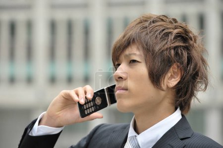 Téléchargez les photos : Jeune homme d'affaires avec téléphone portable en ville - en image libre de droit