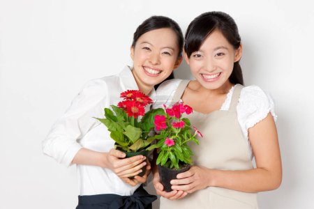 Photo for Young Japanese women holding flowers in flowerpots o white background - Royalty Free Image