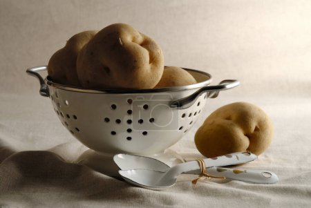 Photo for A colander with potatoes in it and  spoons - Royalty Free Image