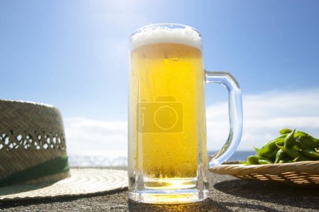 Téléchargez les photos : Bière avec pois verts et chapeau de paille sur fond de bord de mer - en image libre de droit