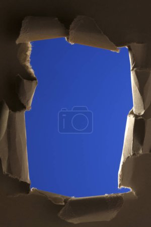 Foto de Agujero en papel roto sobre un fondo azul - Imagen libre de derechos
