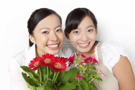 Foto de Jóvenes mujeres japonesas sosteniendo flores en macetas o fondo blanco - Imagen libre de derechos