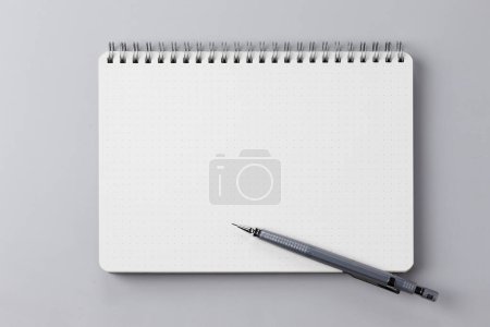 Téléchargez les photos : Bloc-notes avec page blanche et crayon sur fond blanc, vue du dessus - en image libre de droit