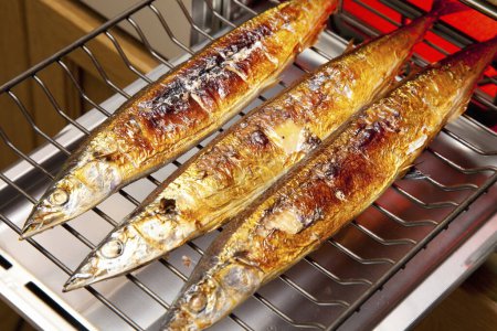 Téléchargez les photos : Trois poissons cuisinent sur un gril dans une cuisine - en image libre de droit