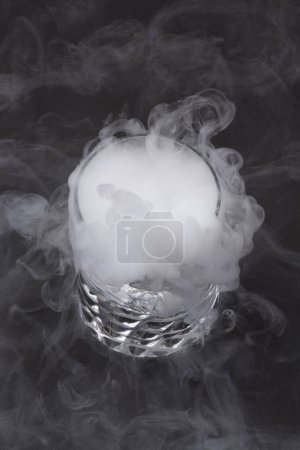 White smoke in glass with the effect of dry ice  on background, close up