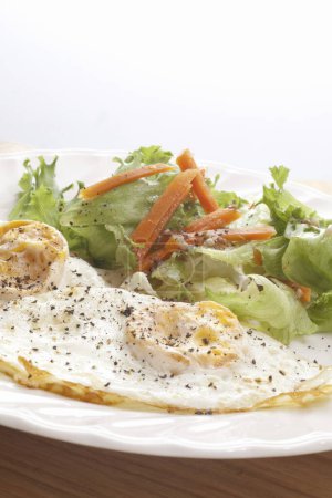 Photo for Omelet with lettuce, fried eggs, tomatoes, onions and lettuce on the plate - Royalty Free Image