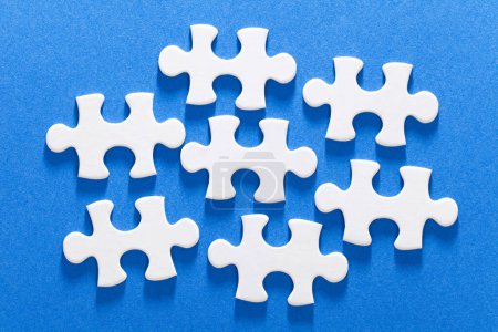 Téléchargez les photos : Un groupe de pièces de puzzle blanc sur une surface bleue - en image libre de droit