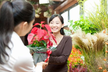 Téléchargez les photos : Portrait de jeune fleuriste japonaise avec cliente en boutique florale - en image libre de droit