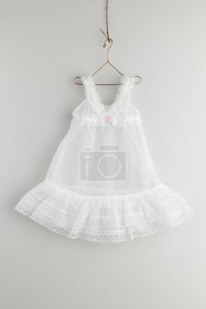 Photo for White  baby dress hanging on hanger. - Royalty Free Image