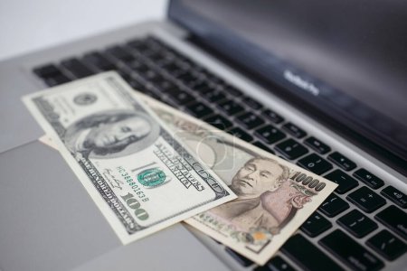 Foto de Una pila de dinero encima de una computadora portátil en el fondo, de cerca - Imagen libre de derechos