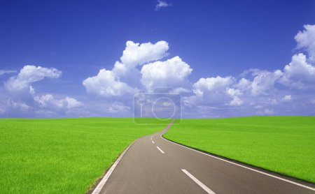 Téléchargez les photos : Route asphaltée et champ d'herbe verte avec ciel bleu et nuages blancs - en image libre de droit