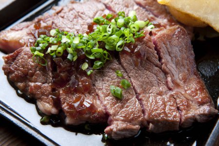 Téléchargez les photos : Un steak avec un côté de pommes de terre et une garniture verte - en image libre de droit