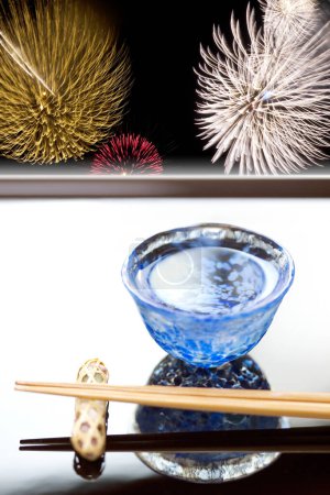 Téléchargez les photos : Vue rapprochée des baguettes placées sur la base de repos et la tasse de saké - en image libre de droit