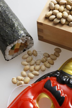 Eho-maki roll, beans for mame-maki (bean-throwing), and demon mask on table. Image of Setsubun