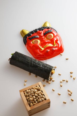 Eho-maki roll, beans for mame-maki (bean-throwing), and demon mask on table. Image of Setsubun