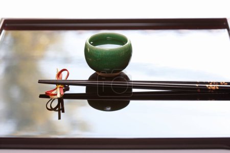 Foto de Vista de cerca de los palillos colocados sobre la base de reposo y la taza de sake - Imagen libre de derechos