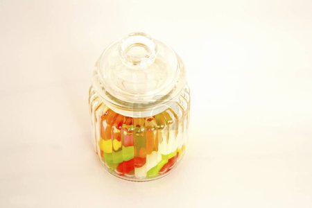 Foto de Caramelos de colores en botella de vidrio sobre fondo blanco - Imagen libre de derechos