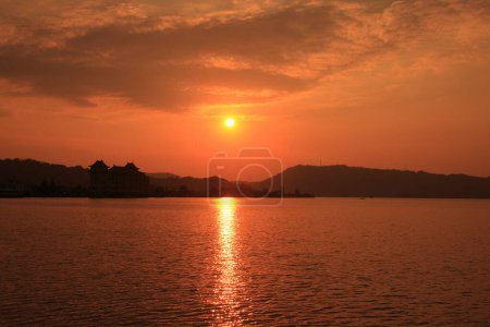 Foto de Una puesta de sol sobre un cuerpo de agua con un barco en el agua - Imagen libre de derechos