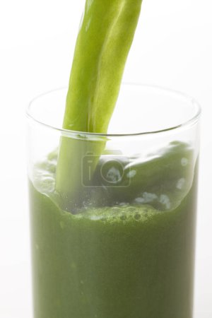 Foto de Vista de cerca de la bebida orgánica fresca verde y saludable vertiendo en vidrio sobre fondo claro - Imagen libre de derechos