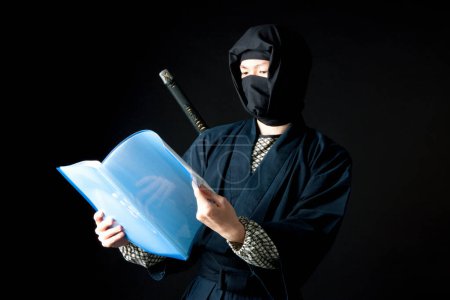 Foto de Joven disfrazado de ninja sosteniendo una carpeta azul - Imagen libre de derechos