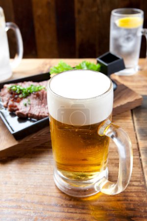 Téléchargez les photos : Un verre à bière avec un steak sur une assiette - en image libre de droit