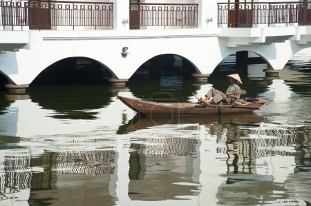 Téléchargez les photos : Homme portant un chapeau de paille vietnamien traditionnel dans le bateau - en image libre de droit