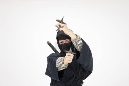 Photo for Young man in a ninja costume holding a star - Royalty Free Image