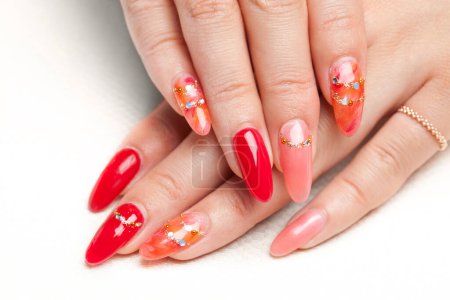 Foto de Manicura roja en uñas femeninas sobre un hermoso fondo - Imagen libre de derechos