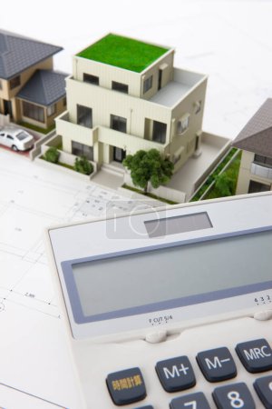 Téléchargez les photos : Modèles de maisons avec calculatrice et plans sur table. concept immobilier - en image libre de droit