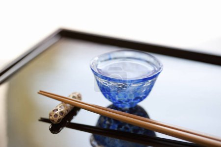 Photo for Close up view of chopsticks placed on resting base and cup of sake - Royalty Free Image
