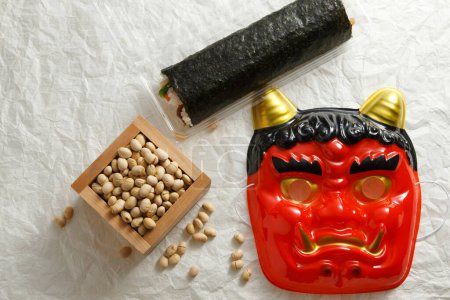 Rollo Eho-maki, frijoles para mame-maki (lanzamiento de frijoles) y máscara de demonio en la mesa. Imagen de Setsubun