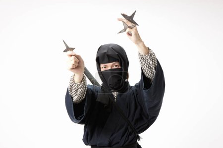 Photo for Young man in a ninja costume holding a stars - Royalty Free Image