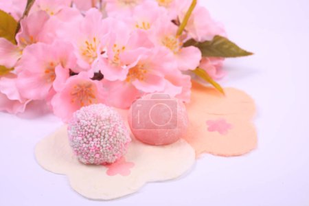 Foto de Vista de cerca de deliciosos dulces japoneses y flores rosadas sobre fondo claro - Imagen libre de derechos