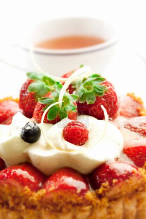 Foto de Sabrosa tarta con fresas y té en el fondo, de cerca - Imagen libre de derechos