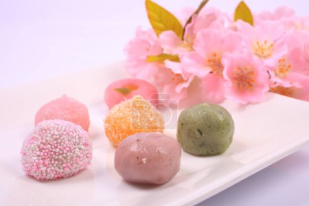 Téléchargez les photos : Vue rapprochée de délicieux bonbons japonais et fleurs roses sur fond clair - en image libre de droit