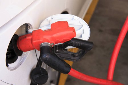 Photo for A red and black gas nozzle is attached to a white car - Royalty Free Image