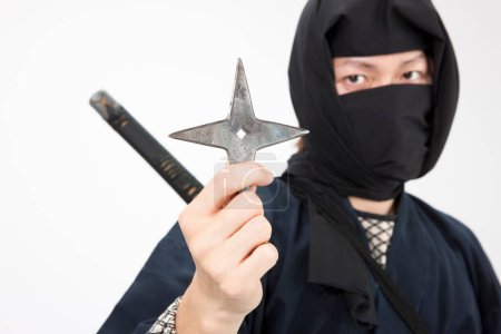 Photo for Young man in a ninja costume holding a star - Royalty Free Image