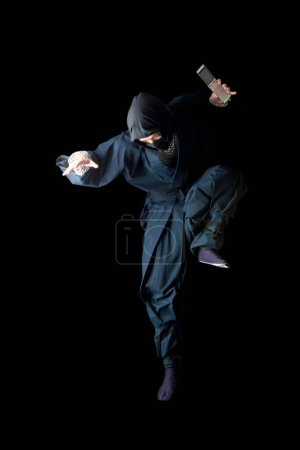 Photo for Man in a black outfit is holding a knife - Royalty Free Image